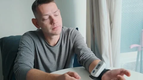 Man using digital wrist blood pressure monitor for measuring blood pressure and Stock Footage 315860057