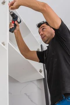 Man using a drill to drive a nail to assemble a piece of furniture Stock Photos