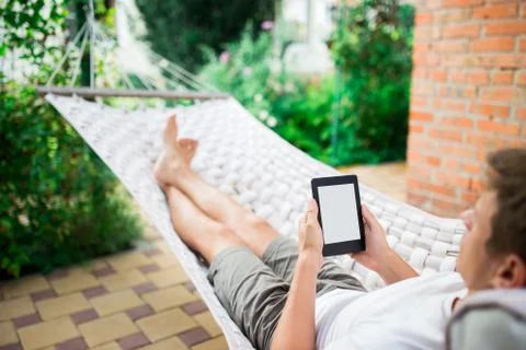 Man using e-book or tablet computer while relaxing in a hammock Stock Photos