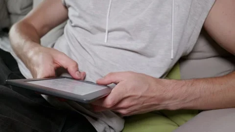 Man Using E-Book Reader Tablet While Relaxing on Couch at Home Stock Footage 339217447