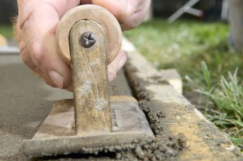 Man using edging tool on wet cement slab close up Stock Photos