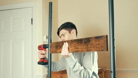 Man using electric drill to attach wooden panel to coat rack. Male assembling Stock Footage 311988468
