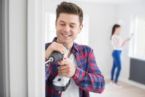 Man Using Electric Drill As Couple Renovate Property Together Stock Photos
