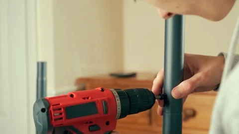 Man using electric drill to fasten screw on coat rack. Male assembling metal Stock Footage 311988409