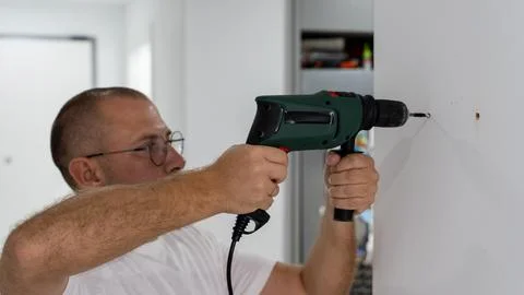 Man Using Electric Drill to Install Wall Fixture During Home Renovation Photos