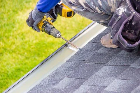Man using an electric drill to secure a rain gutter Stock Photos