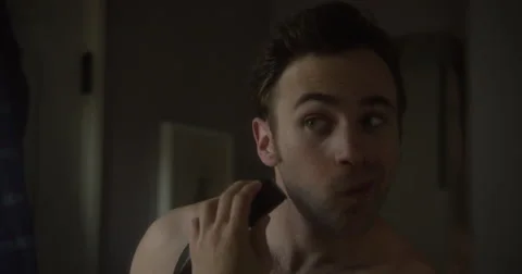 A man using an electric razor in the mirror, trimming his stubble. Stock Footage 64033491
