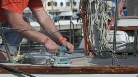 Man using electric sander on the rail of a sailing ship Stock Footage 190380354