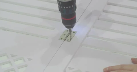 A man using an electric screwdriver screws a screw into a wooden screen board Stock Footage 256046361