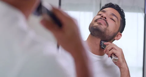 A man is using electric shaver to trim beard while standing in front of mirror. Stock Footage 270505339