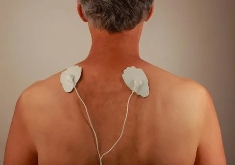 Man using an Electro Therapy Massager or Tens Unit on his back Fotos de archivo