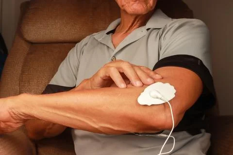 Man using an Electro Therapy Massager or Tens Unit on his elbow Stock Photos