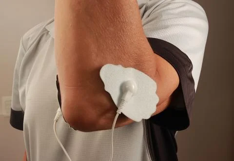 Man using an Electro Therapy Massager or Tens Unit on his elbow Stock Photos