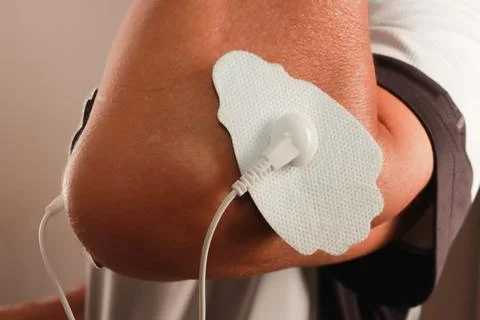 Man using an Electro Therapy Massager or Tens Unit on his elbow Fotos de archivo