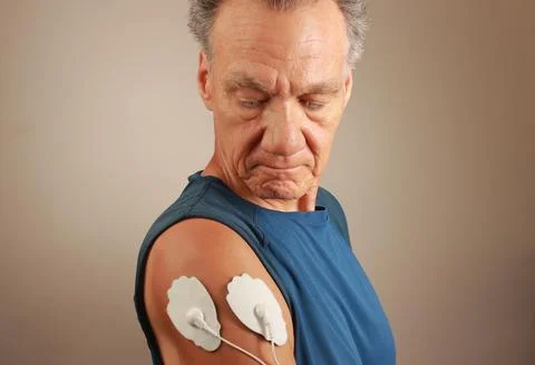 Man using an Electro Therapy Massager or Tens Unit on his Deltoids Stock Photos