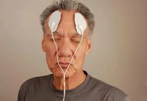 Man using an Electro Therapy Massager or Tens Unit on his forehead 스톡 사진