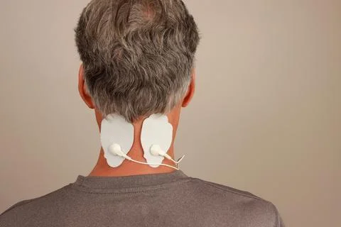 Man using a Electro Therapy Massager or Tens Unit on the back of his neck Stock Photos