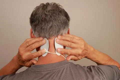 Man using a Electro Therapy Massager or Tens Unit on the back of his neck Stock Photos
