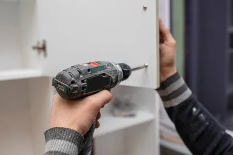 Man using electronic drill to install a cabinet Stock Photos
