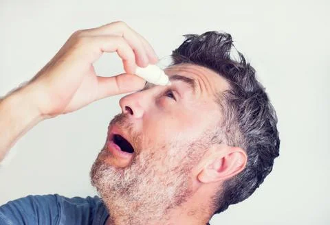 A man using eye drops in eyes Stock Photos