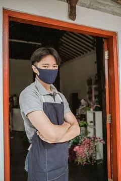 Man using face mask florist standing crossed arm in front door flower shop Stock Photos