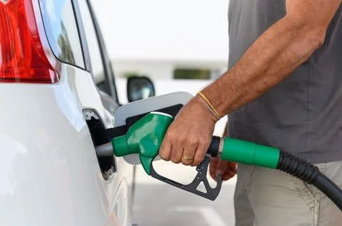 A man using a gas pump to refuel vehicle during energy crisis 库存照片