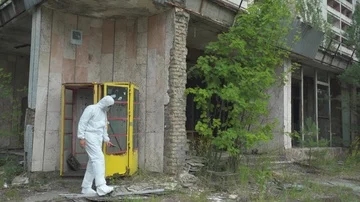 Man using a geiger counter with gas mask and protective suit in Pripyat Stock Footage 86008352