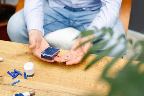 Man using glucometer and stripe for checking blood sugar level at home sitting Stock Photos