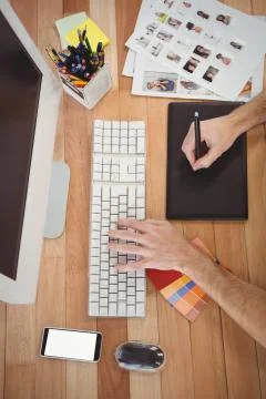 Man using graphics tablet and computer at desk in office Stock Photos