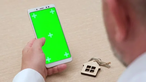 Man using green mobile phone in vertical position near house key Stock Footage 274216610