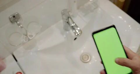 Man Using green screen Cellphone in Bathroom. Video stock 136350564