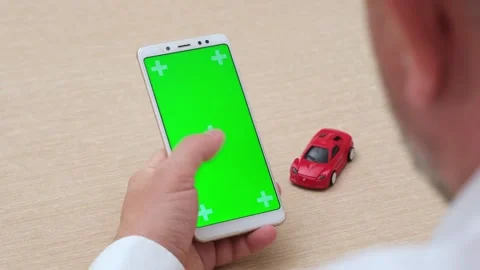 Man using green screen chroma key phone in vertical position near red car model Video stock 275309167
