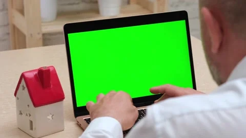 Man using green screen laptop near house model. Buy and sell home online Stock Footage 274343698