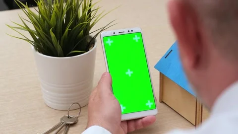 Man using green screen phone over table with house model and keys Stock Footage 284587302