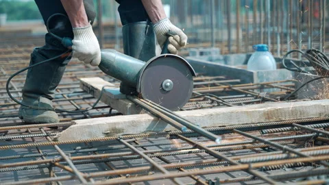 A man is using a grinder to cut a metal bar on a construction site Stock Footage 265478527