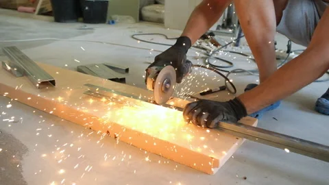 A man using a grinder cuts off a metal profile. close-up. Sparks fly away. Stock Footage 164287534