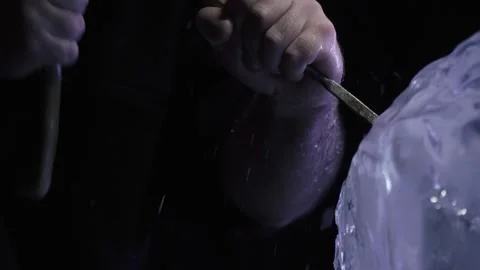 Man is using hammer and chisel to create an ice sculpture in the studio, 4k Stock Footage 153586822