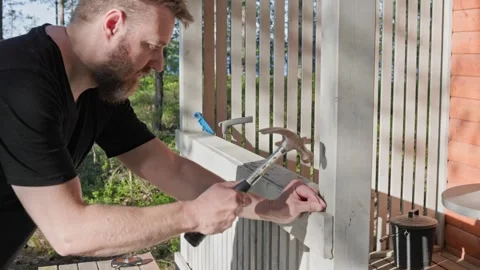 Man using a hammer to drive a nail into the wall at real-time speed. 60fps. Stock Footage 344903165