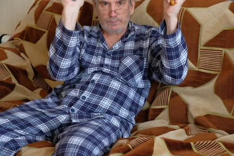 Man using hand expander for strength training on sofa at home Stock Photos