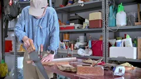 Man Using Hand Saw in Organized Workshop for DIY Woodworking Stock Footage 312730743