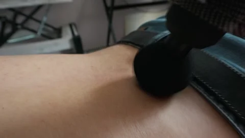 Man Using a Handheld Percussion Massage Gun on His Lower Back at Home Stock Footage 335230879