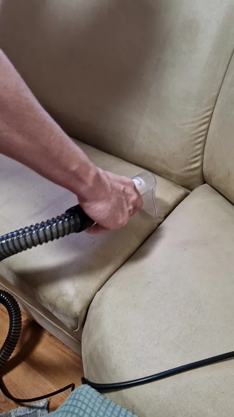 Man Using Handheld Vacuum to Deep Clean Fabric Couch Cushion at Home Video stock 339080837