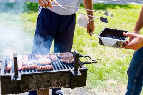 Man is using handle for taking out sausages from barbecue Photos