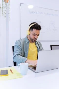 Man using headphones while working with a laptop in the office. Fotos Stock