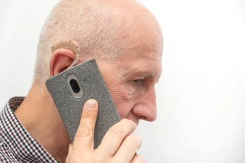 Man using hearing aid while talking on the phone 스톡 사진