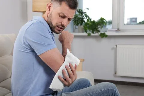 Man using heating pad at home, space for text 库存照片