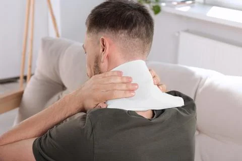 Man using heating pad at home, back view 库存照片