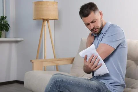 Man using heating pad at home, space for text 库存照片