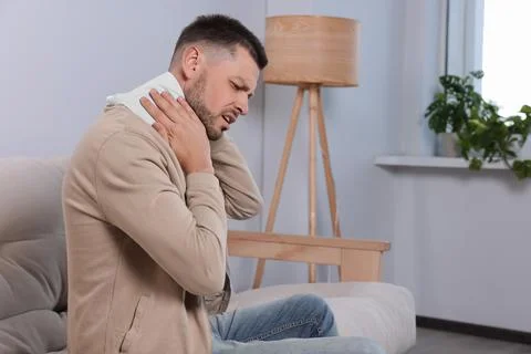 Man using heating pad at home, space for text 库存照片