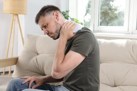 Man using heating pad on sofa at home 库存照片